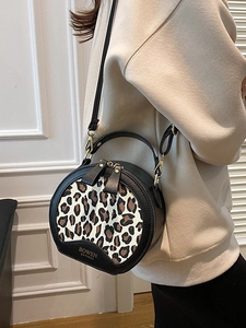 Chic round leopard print handbag with black leather trim and crossbody strap