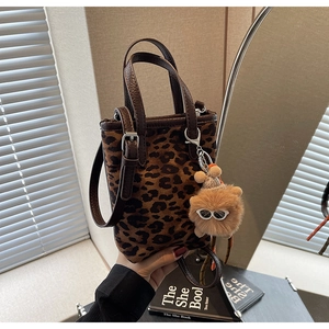 Gros plan du mini sac seau léopard avec pendentif en peluche et bandoulière
