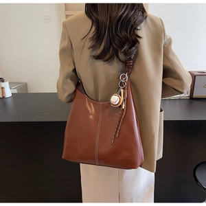 Detail view of large brown PU leather tote with white stitching and baseball charm