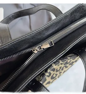 Macro detail of silver metal zipper and black leather with patterned fabric texture