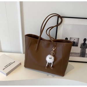 Close-up of a large dark brown tote bag featuring a cute white plush doll keychain