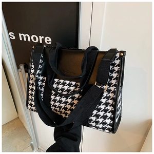 Detail of vintage houndstooth tote bag featuring leather trim and wide fabric strap