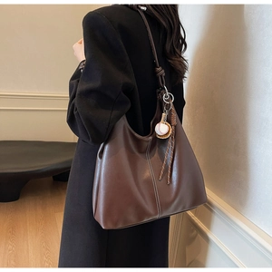Detail of vintage brown tote bag with white contrast stitching and baseball charm