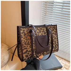 Detail of leopard print tote bag featuring leather pocket and branding in aesthetic setting