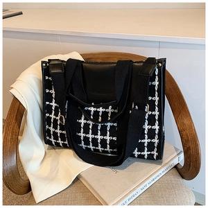 Detail of checkered tote bag with leather拼接 and wide strap on wooden chair