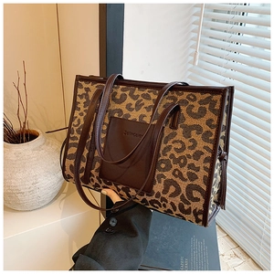 Detailed side view of leopard print tote bag with brown leather handles and logo pocket