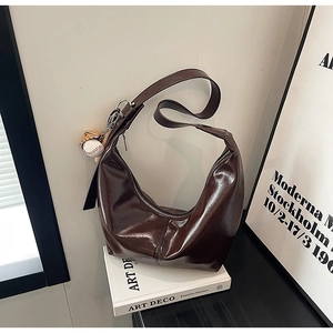 Detail of dark coffee leather hobo bag with adjustable strap and baseball pendant