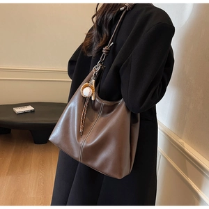 Detail of vintage brown leather tote bag with white stitching and baseball glove charm