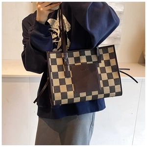 Detail of checkered tote bag featuring a leather front pocket and slim shoulder straps