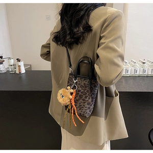 Mini sac seau léopard avec poignées noires et pendentif peluche porté par modèle