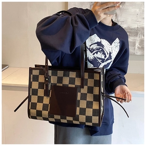 Detail of checkered tote bag with leather logo patch and adjustable side drawstrings