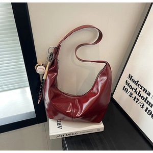 Detail of burgundy glossy semi-moon hobo bag with a decorative baseball theme keychain charm