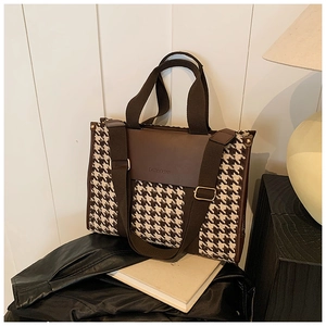 Detail of vintage houndstooth and brown leather tote bag with wide canvas strap