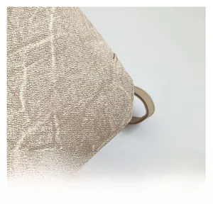 Close-up of textured jacquard fabric with beige and brown geometric patterns and leather handle