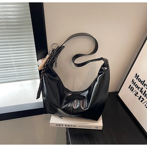 Detail of black semi-moon hobo bag in polished leather with creative baseball charm