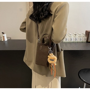 Détail d'un mini sac seau vintage en daim marron avec un charmant ours en peluche