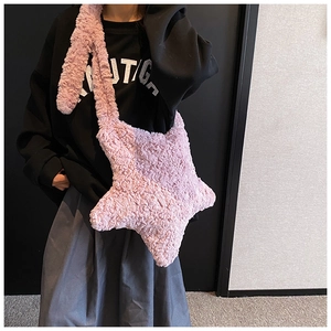 Plush pink star-shaped crossbody bag with wide shoulder strap shown on a model