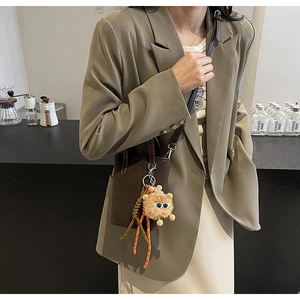Gros plan d'un sac seau vintage marron mat style léopard avec un charm ours en peluche
