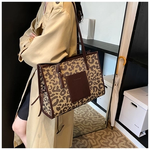 Detailed view of leopard print canvas tote bag with brown leather straps on shoulder