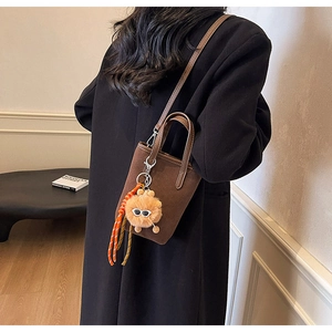 Vue détaillée du mini sac cabas léopard dépoli avec cordon orange et breloque peluche monstre