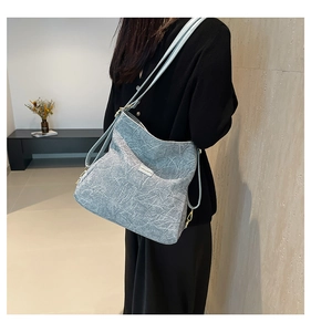 Close-up of light blue textured leather handbag with gold hardware and shoulder strap