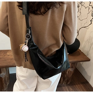Detail of black glossy crescent crossbody bag with creative baseball glove charm