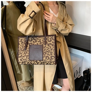 Detail of leopard print canvas tote bag featuring brown leather straps and square logo patch