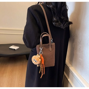 Sac à bandoulière en cuir dépoli marron avec charm lion porté par un mannequin