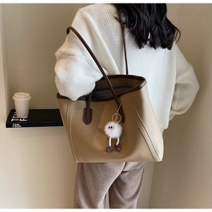 Detail of minimalist tote bag in beige and dark brown with a fluffy eye charm