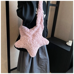 Pink star-shaped plush crossbody bag shown on a model for size and style reference