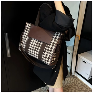 Detail view of houndstooth patchwork tote bag with wide leather strap and logo flap