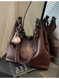 Brown leather tote bag with contrast stitching and baseball charm for daily commute