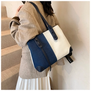 Detailed side view of a large-capacity contrast denim tote bag worn by a model
