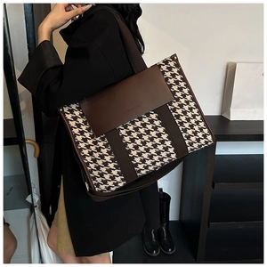 Detail of houndstooth tote bag featuring dark brown leather trim and golden rivets