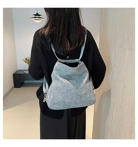 Detail of light blue textured backpack featuring adjustable straps and metal logo plate