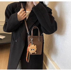 Détail du mini sac seau en daim marron foncé avec charm décoratif et bandoulière fine