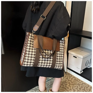 Detail of vintage houndstooth tote bag with brown leather trim and wide shoulder strap