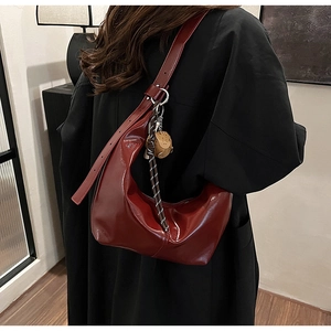 Detail of burgundy glossy leather hobo bag with teddy bear charm shown from back view