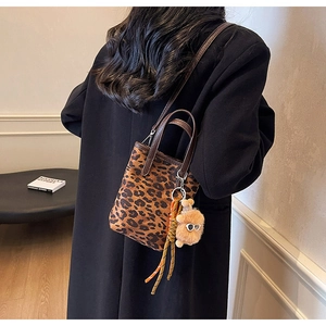 Détail du sac seau léopard avec pendentif ours en peluche et poignée en cuir chic