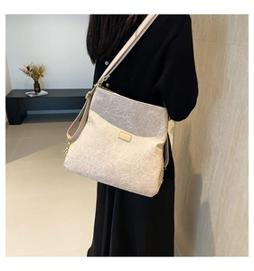 Detailed view of beige crossbody bag with pleated leather texture and gold buckle