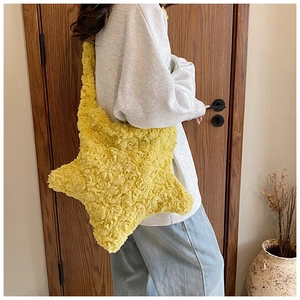 Detailed texture of fluffy yellow star-shaped plush shoulder bag on a female model
