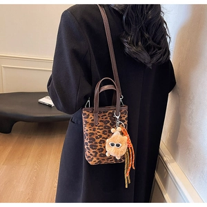 Détail du mini sac léopard avec charm pompon en peluche et bandoulière réglable