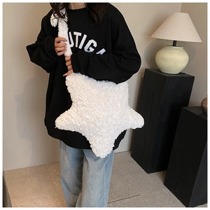 Detailed view of a white plush star-shaped crossbody bag worn by a model in black