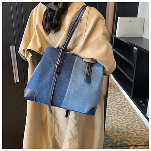 Detail of large capacity denim tote bag showing blue patchwork fabric and leather handles