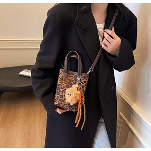 Détail du mini sac seau léopard avec breloque monstre en peluche et anse en cuir