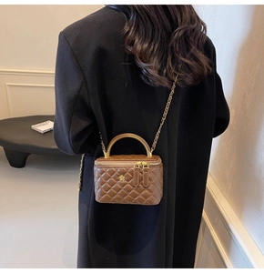 Braune gesteppte Box-Tasche mit Goldblume von Model getragen in einer Lifestyle-Umgebung