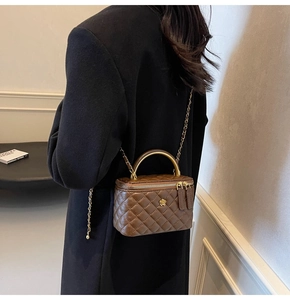 Detailansicht der braunen Stepp-Box-Tasche mit Goldgriff und Blumen-Anhänger