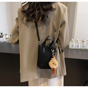 Vue arrière d'un mannequin portant un petit sac bandoulière noir avec charm lion en peluche