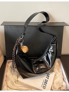 Glossy black hobo shoulder bag with decorative charms on white silk lining