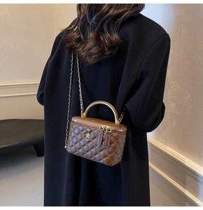 Detailansicht der braunen Stepptasche mit Goldgriff und floralem Hardware-Detail